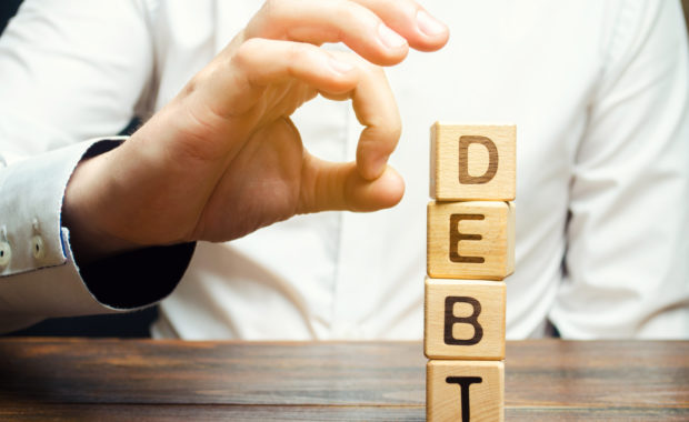 Businessman Removes Wooden Blocks With The Word Debt