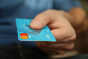 A Person Handing Over a Debit Card and How to Manage Credit Card Debt