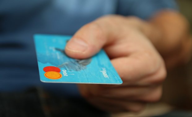 A Person Handing Over a Debit Card and How to Manage Credit Card Debt