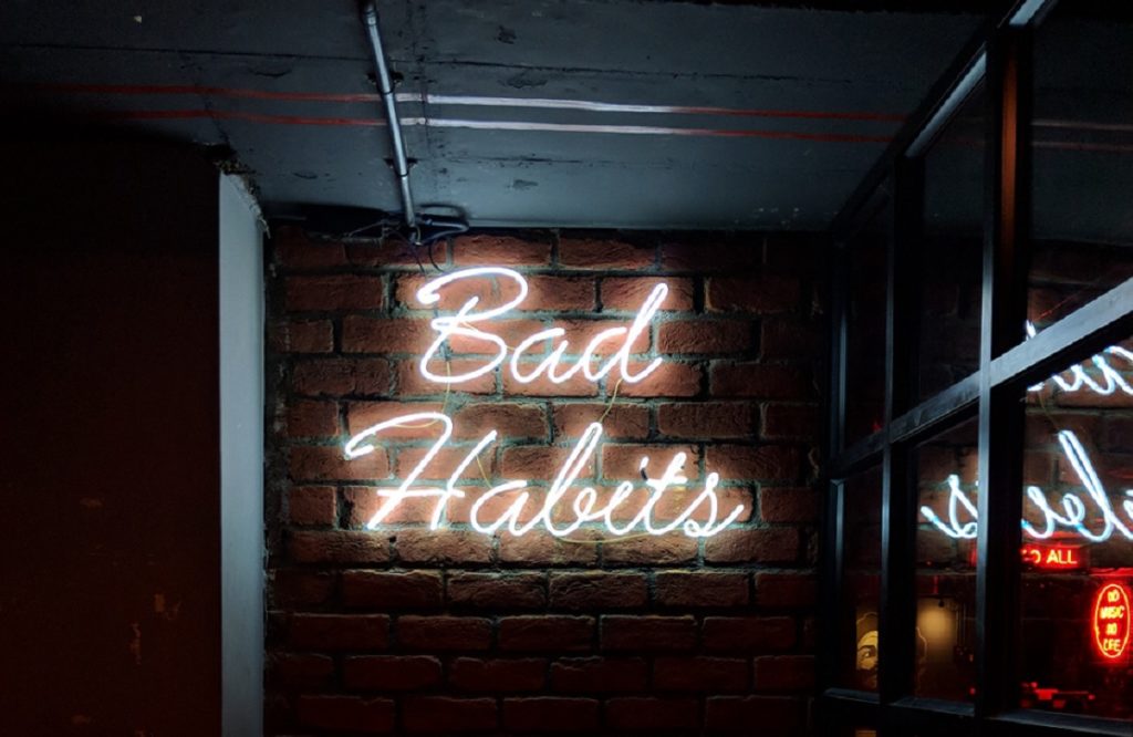 Bad Habits Sign on Brick Walls