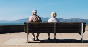 A Retired Couple Sitting On A Park Bench + What does Living Longer mean for Retirement Planning
