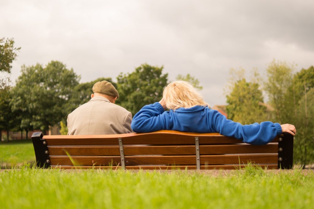 A Retired Couple Sitting On A Park Bench