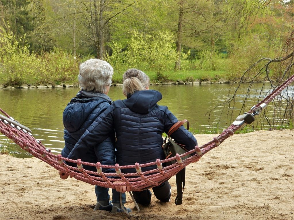 A Women Sitting On A Hammock With Her Mother By The River