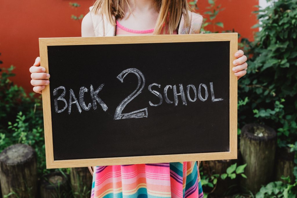 A Child Holding Back 2 School Sign