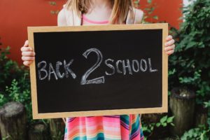 A Child Holding Back 2 School Sign