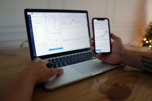 Laptop and Phone Looking at Markets for Long-Term and Short-Term Investing