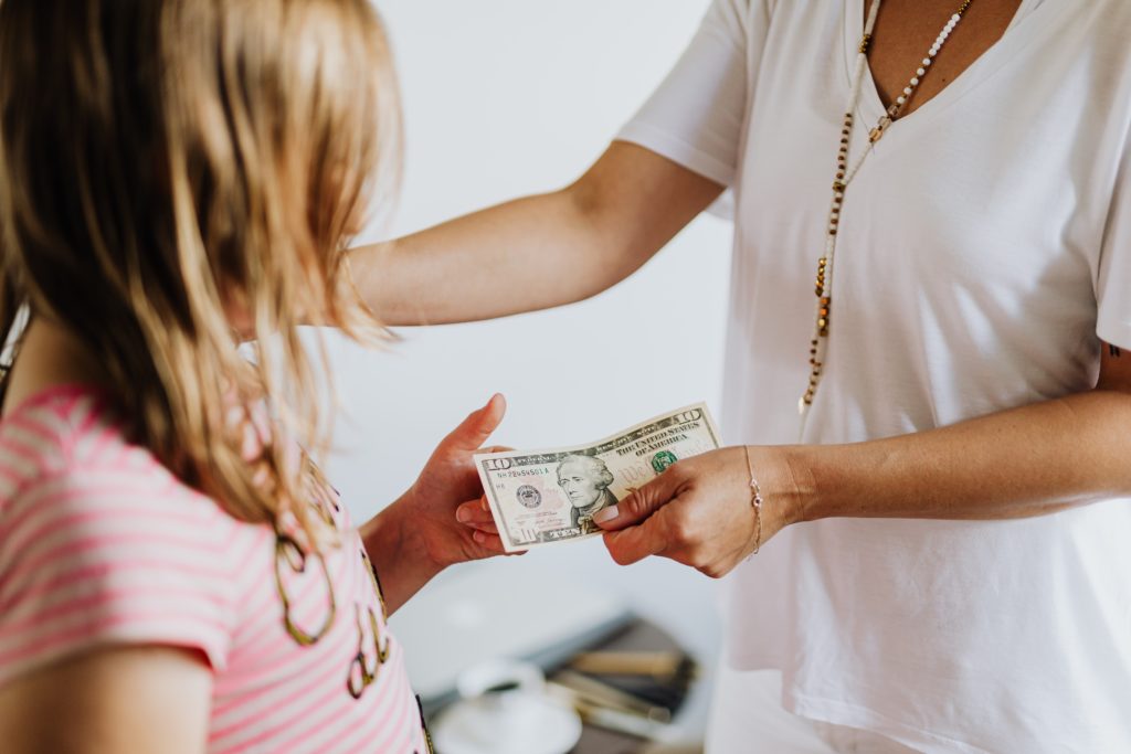 Mother Giving Child Money To Teach Them About Personal Finance + Financial Tips to Share with Your Kids