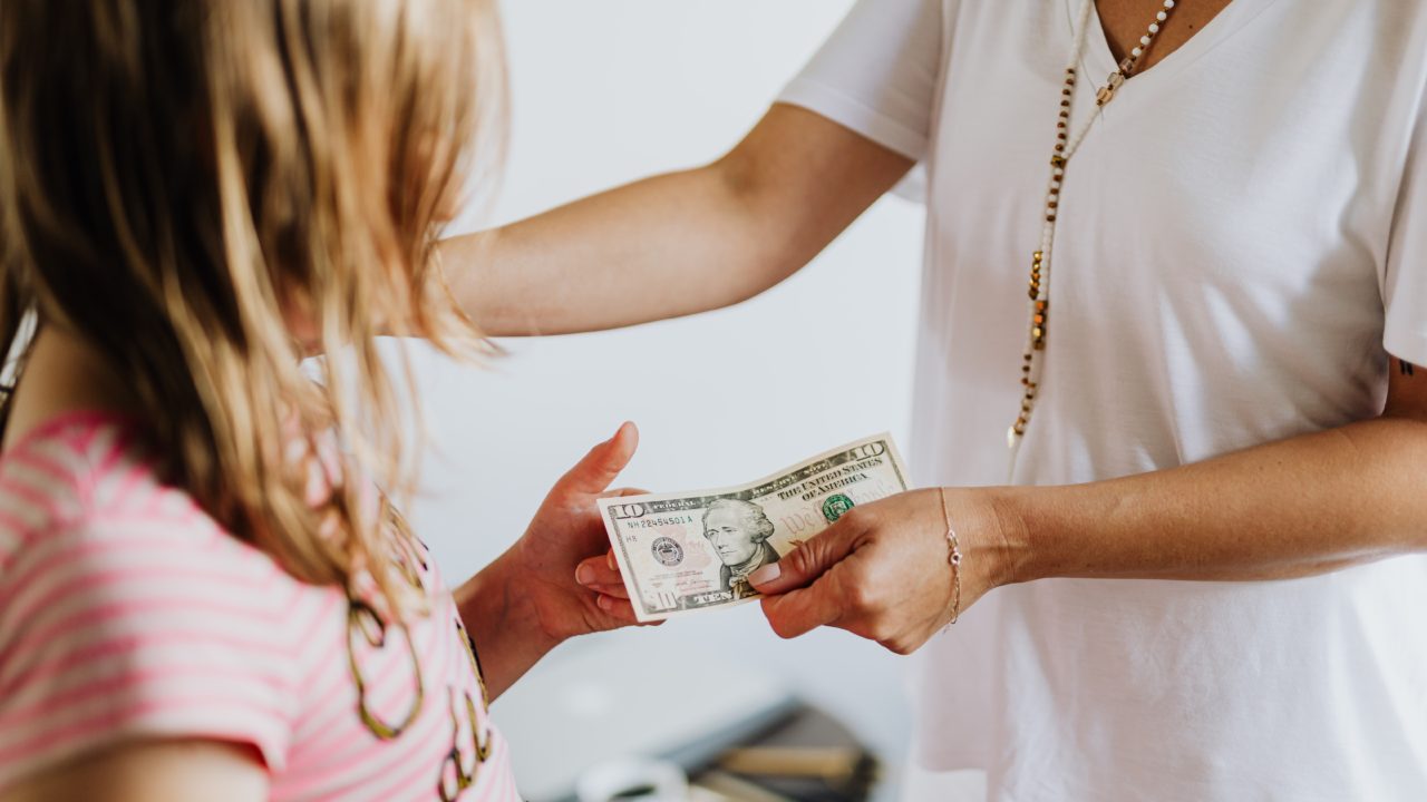 Mother Giving Child Money To Teach Them About Personal Finance + Financial Tips to Share with Your Kids