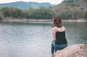 A Women Sitting On A Rock By The Lake + Protecting Your Spouse's Financial Security