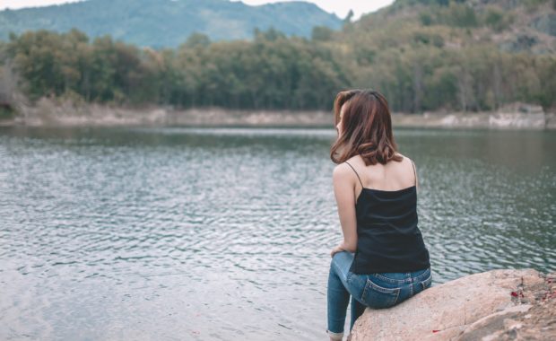 A Women Sitting On A Rock By The Lake + Protecting Your Spouse's Financial Security